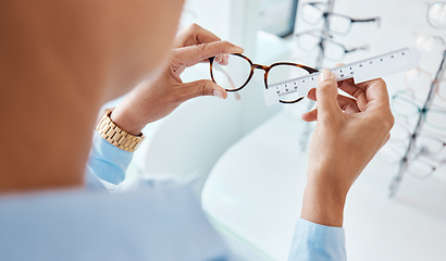 Image showing Optician or optometrist hands measuring and preparing pair of glasses and frame with optic ruler tool. Eye doctor or ophthalmologist determines visual or vision lens size using special eyewear scale.