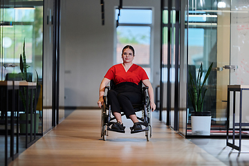 Image showing A modern young businesswoman in a wheelchair is surrounded by an inclusive workspace with glass-walled offices, embodying determination and innovation in the business world