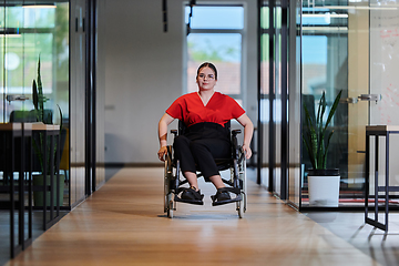 Image showing A modern young businesswoman in a wheelchair is surrounded by an inclusive workspace with glass-walled offices, embodying determination and innovation in the business world