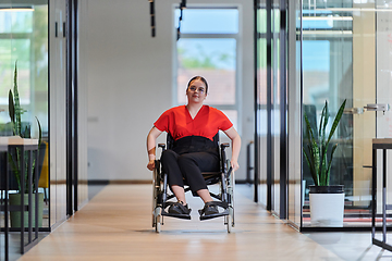 Image showing A modern young businesswoman in a wheelchair is surrounded by an inclusive workspace with glass-walled offices, embodying determination and innovation in the business world