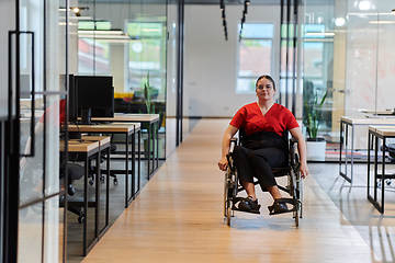 Image showing A modern young businesswoman in a wheelchair is surrounded by an inclusive workspace with glass-walled offices, embodying determination and innovation in the business world