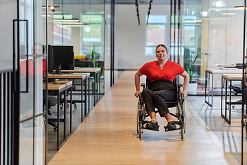 Image showing A modern young businesswoman in a wheelchair is surrounded by an inclusive workspace with glass-walled offices, embodying determination and innovation in the business world