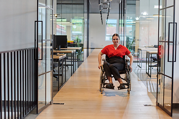 Image showing A modern young businesswoman in a wheelchair is surrounded by an inclusive workspace with glass-walled offices, embodying determination and innovation in the business world