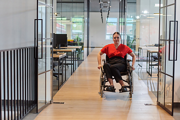 Image showing A modern young businesswoman in a wheelchair is surrounded by an inclusive workspace with glass-walled offices, embodying determination and innovation in the business world