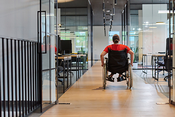 Image showing A modern young businesswoman in a wheelchair is surrounded by an inclusive workspace with glass-walled offices, embodying determination and innovation in the business world