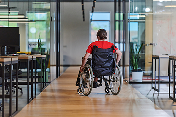 Image showing A modern young businesswoman in a wheelchair is surrounded by an inclusive workspace with glass-walled offices, embodying determination and innovation in the business world