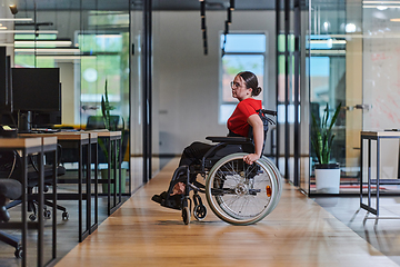 Image showing A modern young businesswoman in a wheelchair is surrounded by an inclusive workspace with glass-walled offices, embodying determination and innovation in the business world