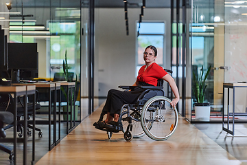 Image showing A modern young businesswoman in a wheelchair is surrounded by an inclusive workspace with glass-walled offices, embodying determination and innovation in the business world