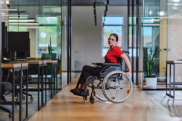 Image showing A modern young businesswoman in a wheelchair is surrounded by an inclusive workspace with glass-walled offices, embodying determination and innovation in the business world