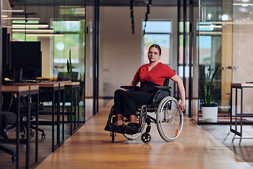 Image showing A modern young businesswoman in a wheelchair is surrounded by an inclusive workspace with glass-walled offices, embodying determination and innovation in the business world