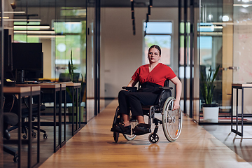 Image showing A modern young businesswoman in a wheelchair is surrounded by an inclusive workspace with glass-walled offices, embodying determination and innovation in the business world