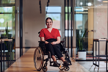 Image showing A modern young businesswoman in a wheelchair is surrounded by an inclusive workspace with glass-walled offices, embodying determination and innovation in the business world