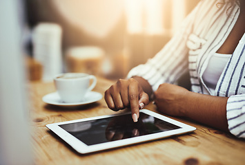 Image showing African woman working on a tablet, sitting in a cafe with coffee alone. Businesswoman using technology to do her job at her desk in the office. Lady casually scrolling the internet in a restaurant.