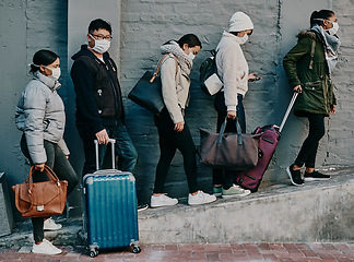 Image showing Traveling people wearing covid face mask and suitcases waiting in line or queue at the airport departure or arrival during a global coronavirus pandemic. Immigration of foreign tourists in quarantine