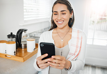 Image showing Woman browsing, texting and reading on a phone in her kitchen at home. Smiling woman on social media online app, networking and messaging contacts while smiling at a funny post, meme or videos