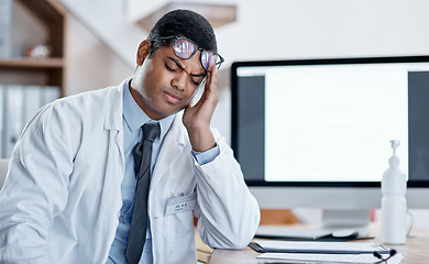 Image showing Doctor suffering from headache, stress and pain while working in a hospital. Young, tired health care professional worker feeling the pressure of a heavy workload during corona virus pandemic