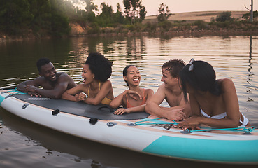 Image showing Friends, vacation and having fun while leaning on a paddle board and talking in a lake. Happy and diverse people laughing while enjoying the water and friendship on their holiday and nature travel