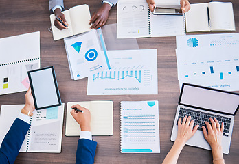 Image showing Financial strategy, growth analysis and planning in meeting with laptop, tablet and graph charts in office. Above desk of diverse group business people analyzing marketing data, report and profit