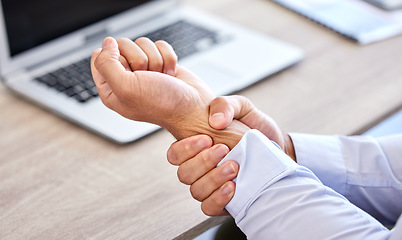 Image showing Business man with bad wrist pain in the hand after an injury and ache while in the office. Closeup of a corporate male with a painful strain, hurtful and sore sitting at his desk