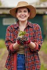 Image showing Sustainable farmer holding a plant or seedling outdoors smiling and happy about her organic farm or garden. Young female nature activist that is passionate about sustainability standing on farmland