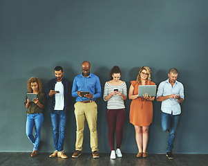 Image showing Diverse group of people browsing social media on a phone, tablet and laptop in studio on a grey background. Networking, surfing the internet and posting online with wireless technology and copyspace