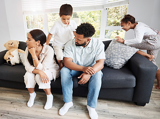 Image showing Frustrated, annoyed and irritated couple sitting on the couch with their hyperactive, noisy and naughty kids fooling around on the sofa at home. Man and woman feeling tired while their children play