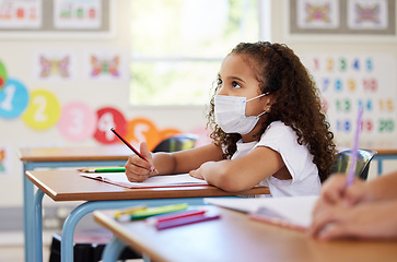 Image showing Education, classroom and learning with covid face mask on girl doing school work, writing and reading at her desk in elementary class. Elementary child wearing protection to stop the spread of virus