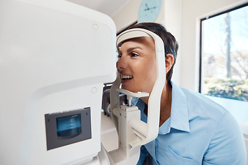 Image showing An eye test, exam or screening for vision and eyesight at the optometrist or optician with a young woman. Testing her sight with an automated refractor for prescription glasses or contact lenses