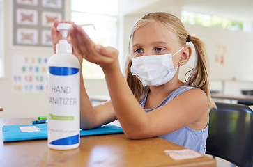 Image showing Little student sanitizing hand to protect from covid, wearing a mask and following new hygiene safety routine. Kindergarten or preschool female learner protecting herself from corona virus flu