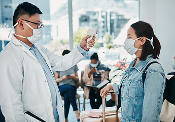 Image showing Covid traveling with a doctor taking temperature of a woman wearing a mask in an airport for safety in a pandemic. Healthcare professional with an infrared thermometer following travel protocol