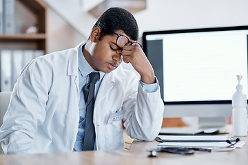 Image showing Stressed, tired young male doctor at his office desk in a hospital. Medical or healthcare man exhausted with pain and headache or sore eyes at the workplace from overworking and burnout