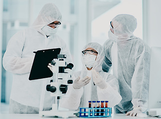 Image showing Science and medical research doctors working on covid vaccine test while wearing protective hazmat suits in modern medicine laboratory. Group of healthcare scientists discussing blood treatment