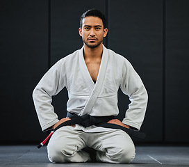 Image showing . Male coach ready for karate training at fitness studio, looking serious at dojo practice in gym and sitting on the floor at a self defense class. Portrait of tough, healthy and active trainer.