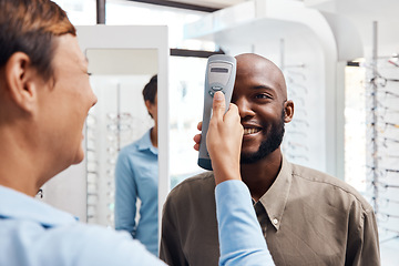 Image showing Eye exam, eyewear and an optometrist checking happy young male eyes with optic medical equipment. African man getting his eyesight checked by a tonometer. Smiling guy getting new spectacles.