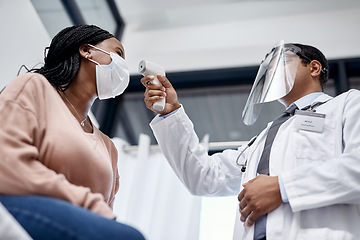 Image showing Covid screening with a doctor measuring temperature of a patient using an infrared thermometer during an appointment or checkup. Female getting tested for corona virus and wearing a mask from below