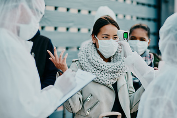 Image showing Health care worker scanning a frustrated woman temperature for corona with a thermometer. Concerned female made victim of racial profiling, looking annoyed and angry during the pandemic