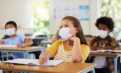 Image showing Focused young girl in school after covid pandemic, sitting and listening in classroom while taking notes. Small child looking at board, learning and thinking for her education with other students