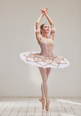 Image showing Female ballerina doing ballet dance, dancing or performing during a practice rehearsal in studio. Young dancer or artist in a tutu costume dress and shoes doing pointe technique on toes performance