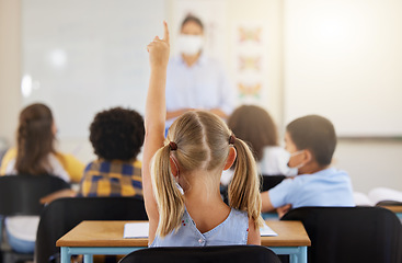 Image showing Learning, smart and little girl in class holding up a hand to answer a question at school. Back view of a young student sitting at a classroom desk looking to solve the questions a teacher is asking