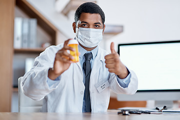 Image showing Trustworthy doctor selling good covid medicine or bottle of pills, approving successful medication in hospital. Male healthcare or medical professional wearing mask, showing thumbs up hand gesture.