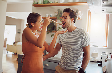 Image showing Fun, food and young couple cooking in a kitchen at home, bonding while being playful and looking happy. Husband and wife tasting and flirting, preparing food and fooling around together