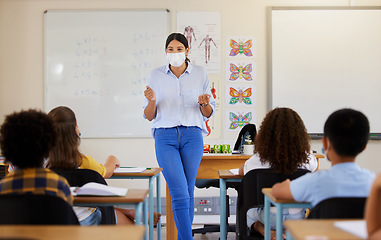 Image showing Young female teaching after covid pandemic, in classroom with young children students, in face mask. Back to school for little kids learning their education from their teacher after quarantine