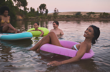 Image showing Vacation, swimming and friendship having fun in a lake while enjoying the summer sunset. Happy friends relaxing and floating in water while talking and bonding on a getaway holiday