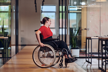 Image showing A modern young businesswoman in a wheelchair is surrounded by an inclusive workspace with glass-walled offices, embodying determination and innovation in the business world