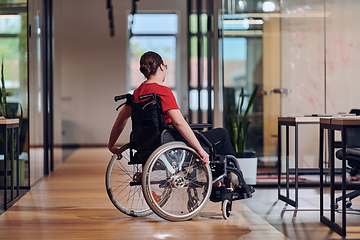 Image showing A modern young businesswoman in a wheelchair is surrounded by an inclusive workspace with glass-walled offices, embodying determination and innovation in the business world