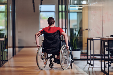 Image showing A modern young businesswoman in a wheelchair is surrounded by an inclusive workspace with glass-walled offices, embodying determination and innovation in the business world