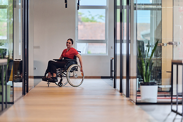 Image showing A modern young businesswoman in a wheelchair is surrounded by an inclusive workspace with glass-walled offices, embodying determination and innovation in the business world