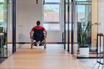 Image showing A modern young businesswoman in a wheelchair is surrounded by an inclusive workspace with glass-walled offices, embodying determination and innovation in the business world