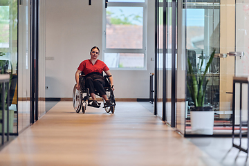 Image showing A modern young businesswoman in a wheelchair is surrounded by an inclusive workspace with glass-walled offices, embodying determination and innovation in the business world