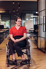 Image showing A modern young businesswoman in a wheelchair is surrounded by an inclusive workspace with glass-walled offices, embodying determination and innovation in the business world